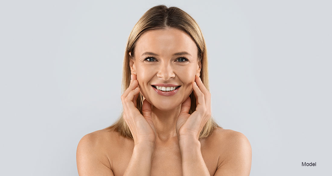 woman smiling and touching her face